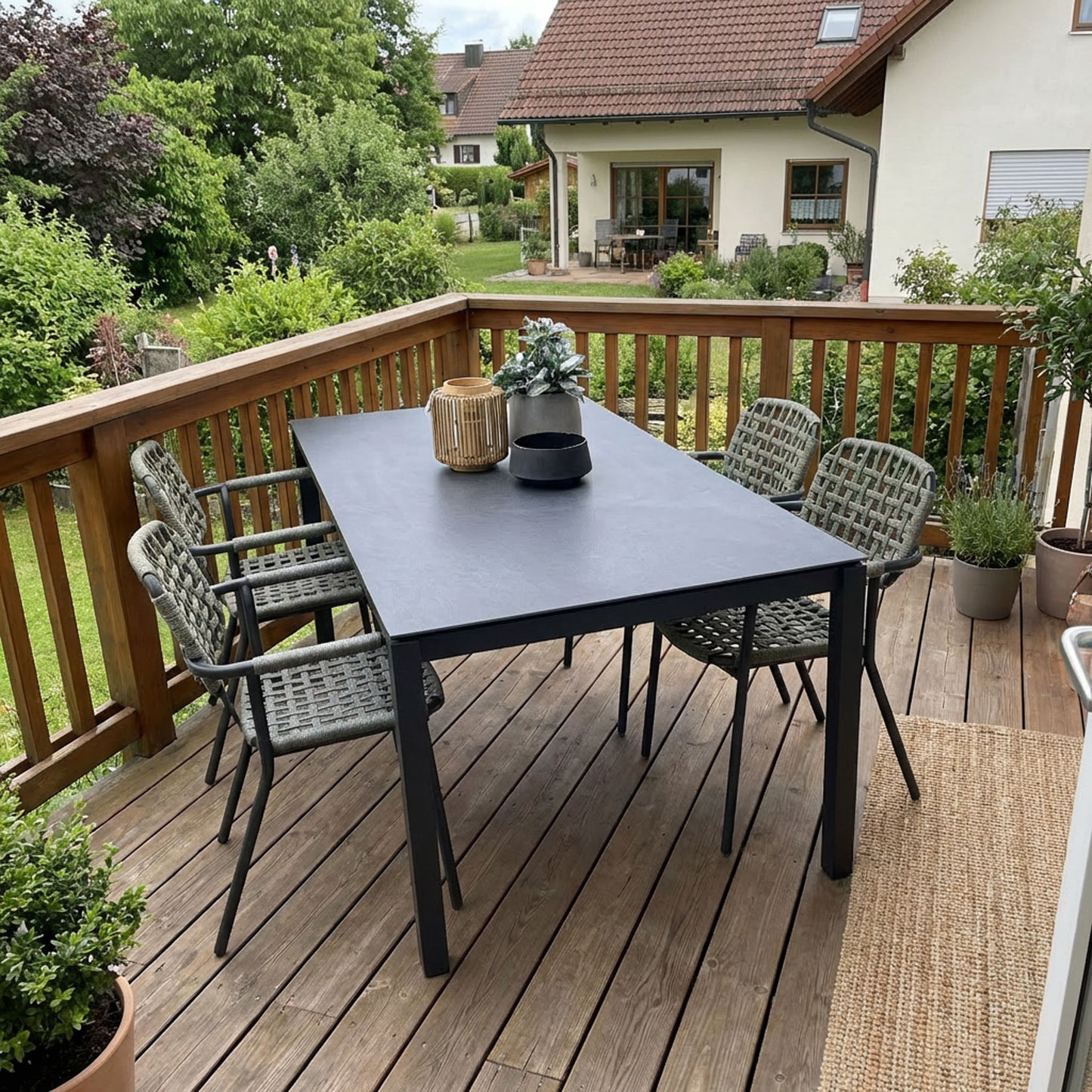schwarzer Gartentisch mit grünen Flechtstühlen auf Balkon