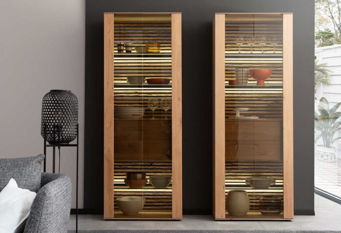 Ein Highboard in Holzoptik mit eleganter Beleuchtung vor einer schwarzen Wand